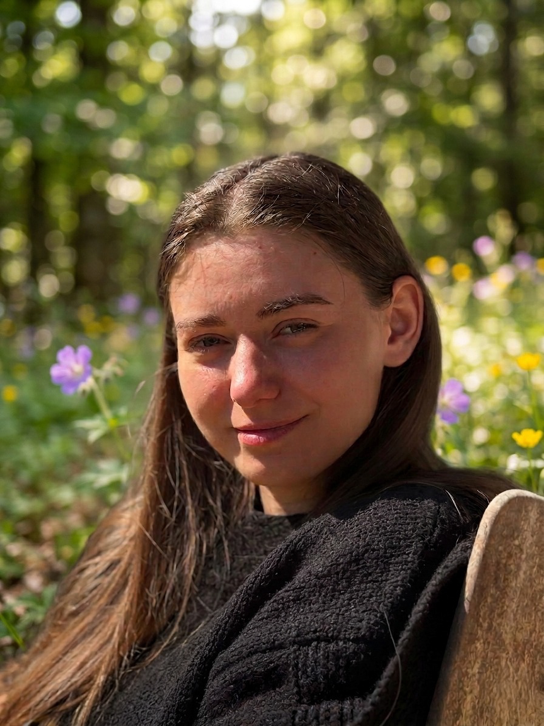 Portrait of Video Editor Anastasia Velt sitting in front of a window, smiling and looking off to the side